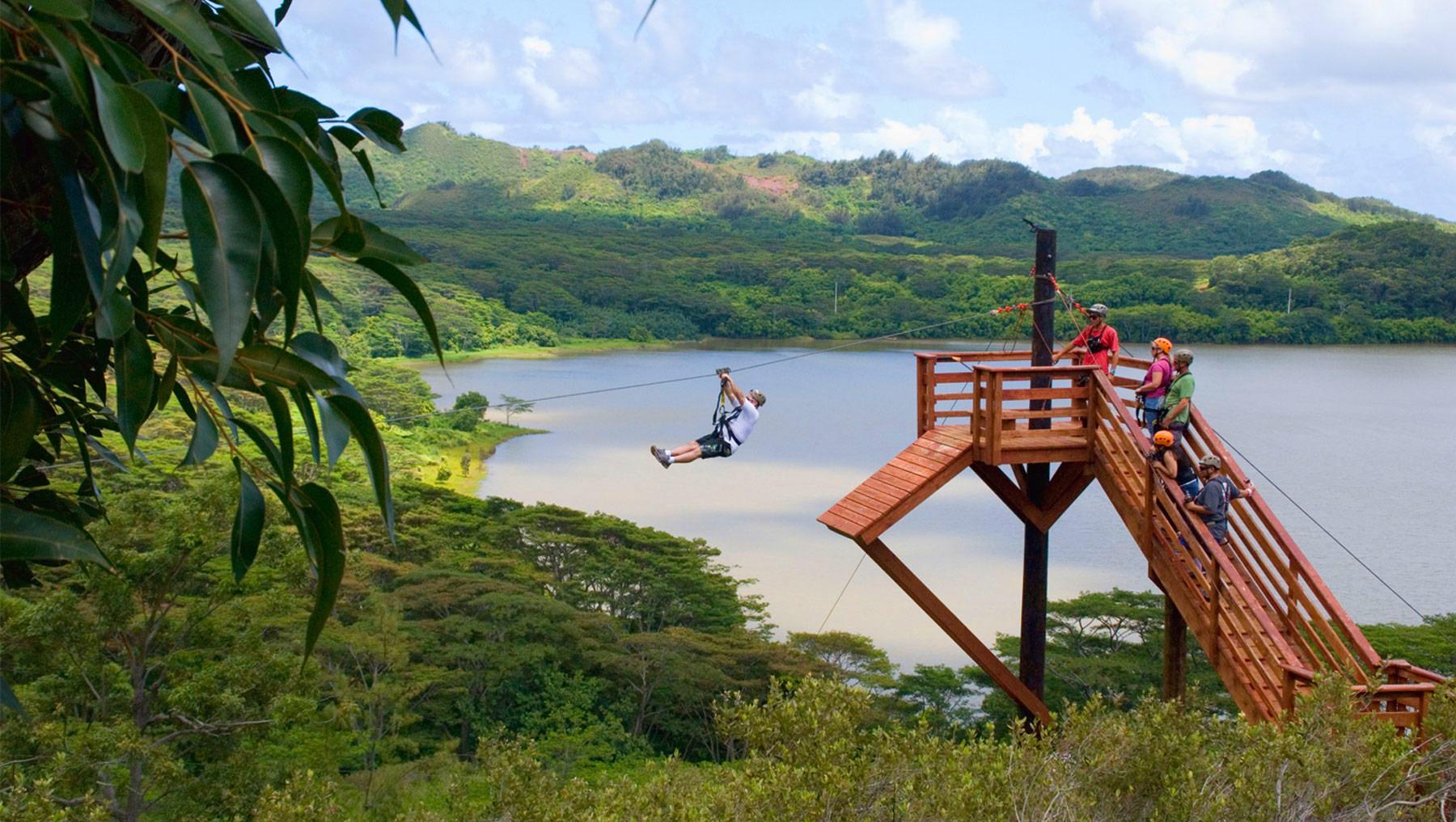 A guest launches from a Koloa Zipline platform above the reservoir