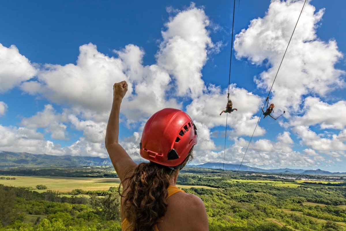 A guest cheers as two riders fly side by side above Kīpū Ranch